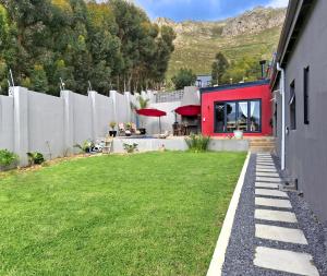 a house with a grass yard next to a building at Getaway between the sea and the mountains in Gordonʼs Bay