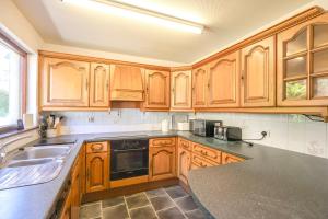 a kitchen with wooden cabinets and a black counter top at Ardmara in Belladrum