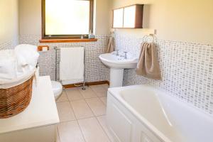 a bathroom with a sink and a toilet and a tub at Ardmara in Belladrum +21 photos