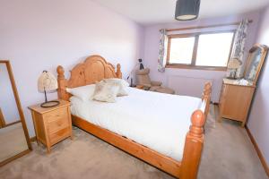 a bedroom with a large wooden bed with white sheets at Ardmara in Belladrum