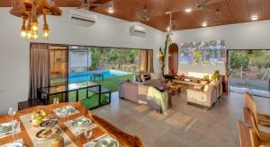 a living room with a pool in the background at SaffronStays Ivy Courtyard - 5 bedroom & Veg Only Villa in Khopoli in Jambhulpāda