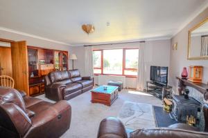 a living room with leather couches and a television at Ardmara in Belladrum