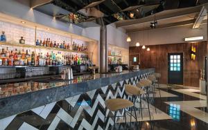 a bar with bar stools and bottles of alcohol at Heathcote Hotel Manchester in Manchester