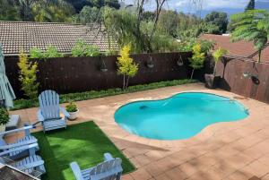 a small swimming pool in a yard with two chairs at Berg and Dal in Paarl
