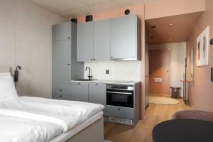 a bedroom with a bed and a kitchen with white cabinets at Aarni Property in Jyväskylä