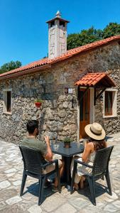 a man and woman sitting at a table in front of a building at Stone Cottage O CEBREIRO in Curtis