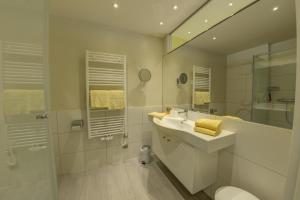 a white bathroom with a sink and a shower at Seepark Drobollach in Drobollach am Faaker See +200 photos