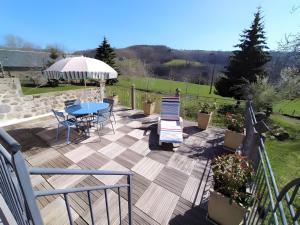 a deck with a table and chairs and an umbrella at Gîte de Pradevin in Jou-sous-Monjou +15 photos