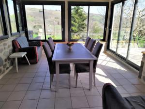 a table and chairs in a room with windows at Gîte de Pradevin in Jou-sous-Monjou