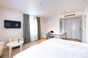 a white hotel room with a bed and a desk at Garner Hotel Post Aschaffenburg by IHG in Aschaffenburg