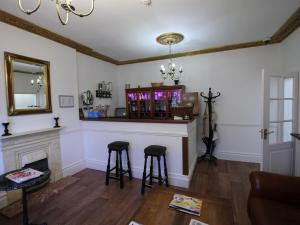 Eine Bar im Wohnzimmer mit zwei Barhockern in der Unterkunft Thanington hotel in Canterbury
