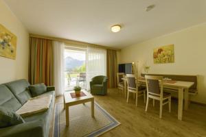 a living room with a couch and a dining room at Seepark Drobollach in Drobollach am Faaker See