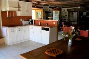 a kitchen with white cabinets and a wooden table at Gîte de Pradevin in Jou-sous-Monjou