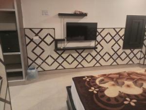 a living room with a tv and a wall at Fivee Hotel Model Town Multan in Multan +18 photos