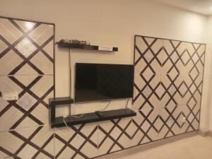 a wall with a mirror and a tv in a room at Fivee Hotel Model Town Multan in Multan