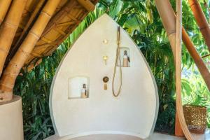 a wall with a clock in front of plants at Green Earth Bali luxury Bamboo villas in Sidemen +71 photos