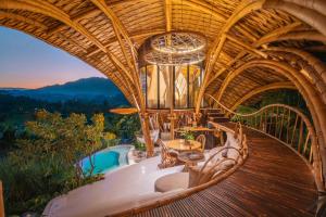 a large room with a deck with a table and chairs at Green Earth Bali luxury Bamboo villas in Sidemen