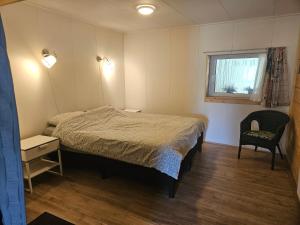 a small bedroom with a bed and a chair at Little Creek - Lodges in het natuurgebied in Renesse