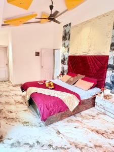 a bedroom with a large bed with a red headboard at Eko Nest Grand 5BHK Villa in Lonavala