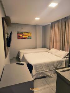 a hotel room with two beds and a window at Uno Flats - By EasyHost in Tambaú +60 photos