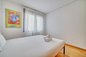 a white bedroom with a white bed and a window at Las Gaunas by Clabao in Logroño +26 photos