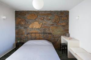 a room with a bed and a stone wall at Kelya Houses in Kithnos