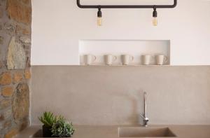 a kitchen sink with three coffee cups on a shelf at Kelya Houses in Kithnos +19 photos