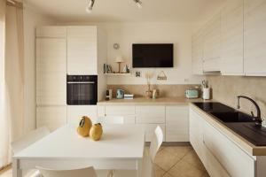 a kitchen with white cabinets and a white table at Badesi Sea Dunes in Codaruina +12 photos