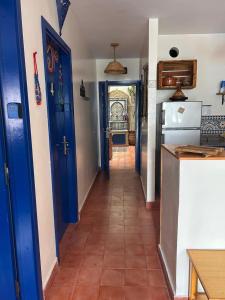 a hallway of a kitchen with blue doors and a tile floor at Tigmi Blue - Imsouane Surf et Océan in Imsouane
