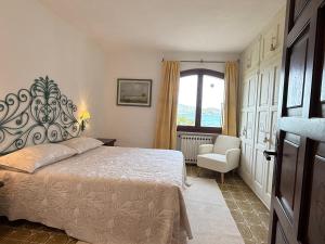 a bedroom with a bed and a chair and a window at Villa Annalia in Cannigione