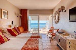 a hotel room with two beds and a view of the ocean at Roc Hotel - Hôtel 4 étoiles les pieds dans l'eau in Le Lavandou