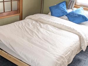 a bed with white sheets and blue pillows on it at 碧 AO Antik&Bay in Takamatsu