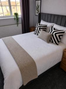 a bed with black and white pillows on it at The Grimsby Heneage Stay in Grimsby +1 photo