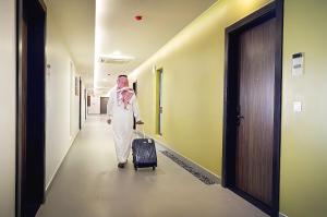 a woman walking down a hallway with a suitcase at AFAM Residence in Dammam
