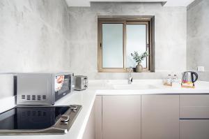 a white kitchen with a sink and a microwave at AFAM Residence in Dammam