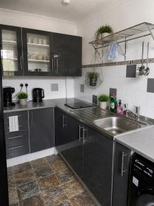 a kitchen with black cabinets and a sink at The Grimsby Heneage Stay in Grimsby