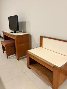 a bedroom with a bed and a desk with a tv at Hotel Mata da Praia in Vitória