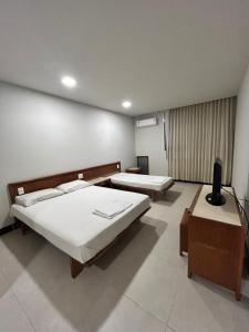 a room with two beds and a television in it at Hotel Mata da Praia in Vitória