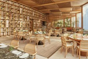 a restaurant with tables and chairs and a wall of books at The Red Sea EDITION in Ḩanak