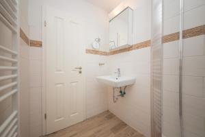 a white bathroom with a sink and a mirror at Schleiblick App 11 in Rabenkirchen-Faulück