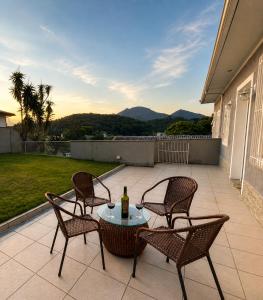 a patio with three chairs and a table with a bottle of wine at Casa Aconchegante com Vista pertinho do Centro Histórico in Petrópolis