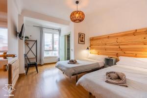 a bedroom with two beds and a wooden wall at AtuaireHome Hostal en el centro de Burgos in Burgos +59 photos