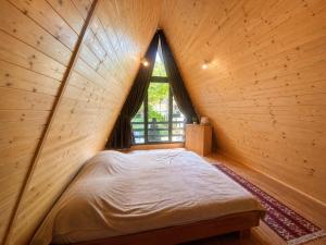 a bed in a wooden room with a window at Căbănuțe Izbândiș in Şuncuiuş