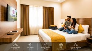 a man and woman sitting on a bed in a hotel room at Urban Comforts - Near US Consulate Business Hotel in T Nagar in Chennai