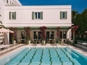 a swimming pool in front of a white house at The Vineta Hotel, Oetker Hotels in Palm Beach