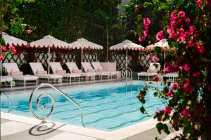 a swimming pool with chairs and umbrellas and pink flowers at The Vineta Hotel, Oetker Hotels in Palm Beach +10 photos