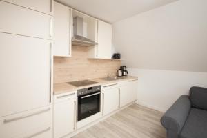 a small kitchen with white cabinets and a couch at Schleiblick App 7 in Rabenkirchen-Faulück