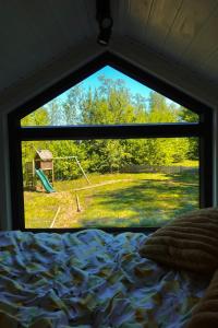a bedroom window with a view of a playground at Prullenbos Tiny House Nutz Nest in Wetteren
