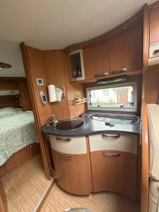 a small kitchen with a sink and a bed at Camping car Paris in Savigny-le-Temple