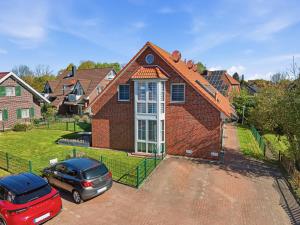 a red brick house with a car parked in a driveway at Grachtenperle in Greetsiel